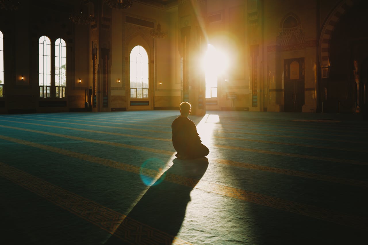 about-02 A person praying in a sunlit mosque in Malaysia, capturing tranquility and spirituality.