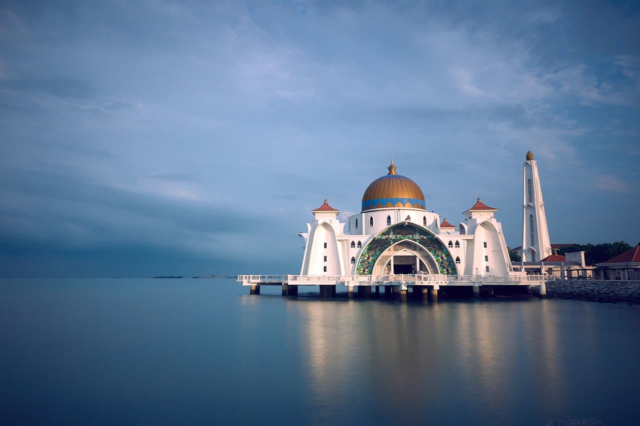 why-choose-us-02 Capture of the majestic Malacca Strait Mosque in serene twilight reflecting upon calm waters.