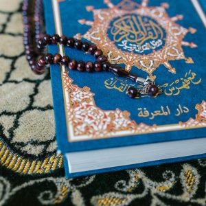 A Quran with prayer beads on a decorative carpet, symbolizing Islamic spirituality.